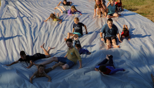 A crowd of tutor kids descends the slide