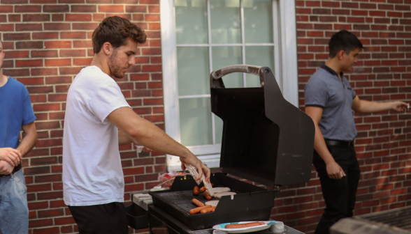 A senior grills hot dogs