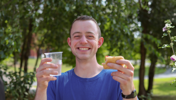 A student poses with a hotdog and a drink