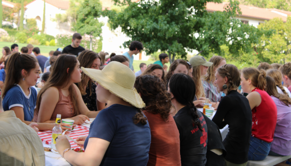 Students dine at long picnic tables