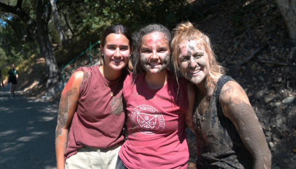 Three pose for a photo, mud-covered