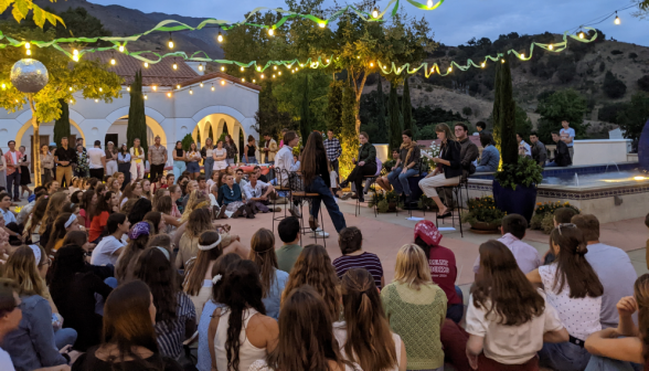 Five perform a skit, surrounded by seated students