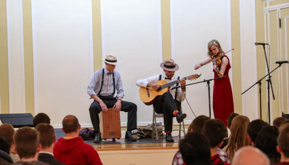 A trio -- drummer, guitarist, and violinist -- perform