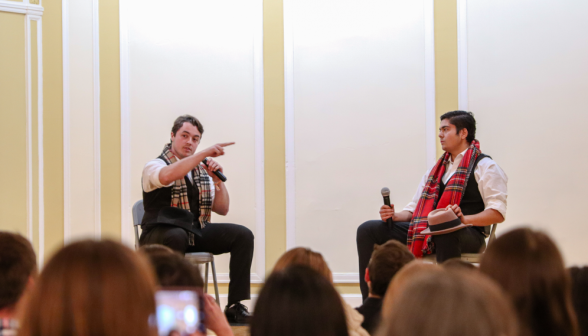 Two perform a skit in scarves and vests