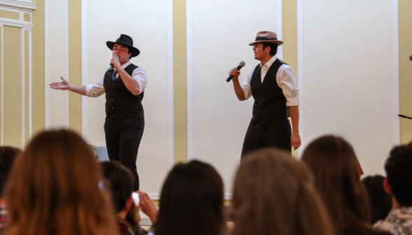 The two performers, now clad in hats, continue the skit