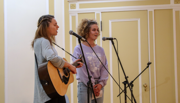 A duo performs: one on guitar, and both singing