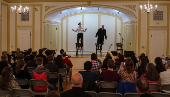 Two perform a skit standing on chairs