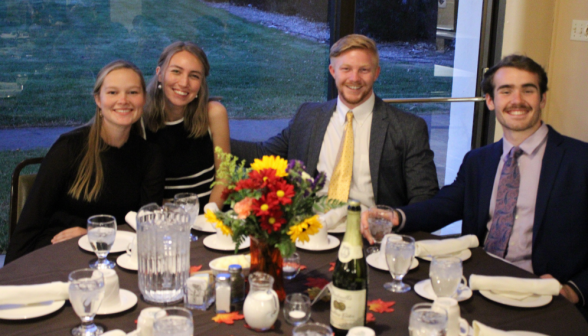 Four at a table pose for a photo