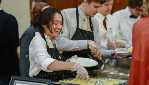 A smiling server serves mashed potatoes