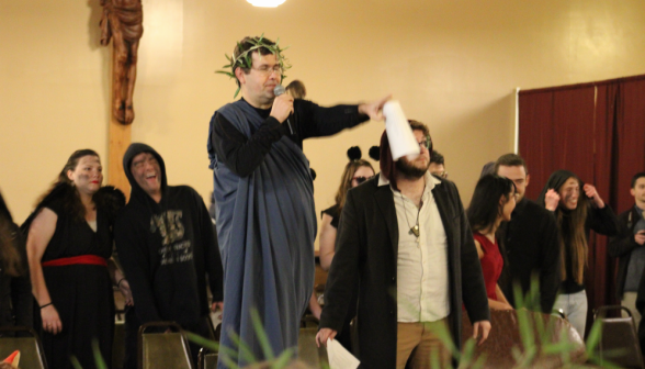 A student in toga and laurel wreath with the mic