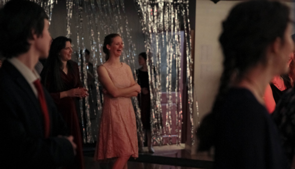 Student in front of the glittery wall look on at the goings-on