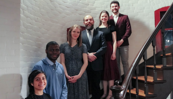 Six pose for a photo on the stairs