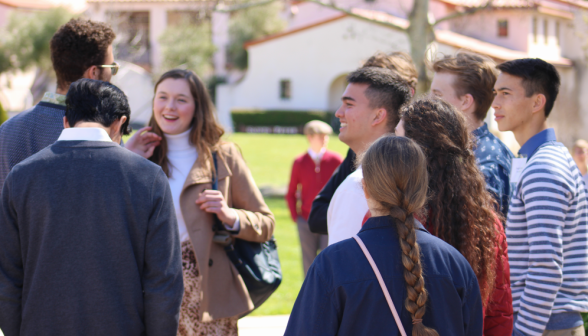 A group of visitors chats with a student outdoors