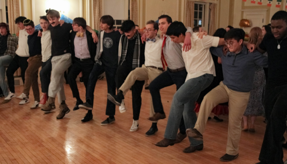 Arms linked, students perform a group dance