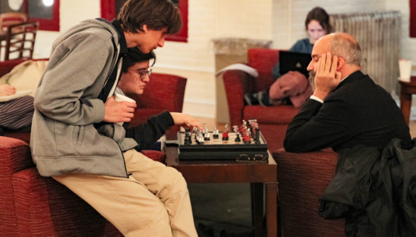 Fr. Viego plays chess with a student while another watches