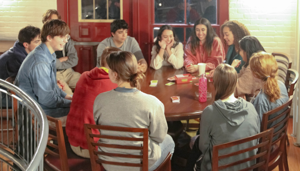 Students play a card game around a table