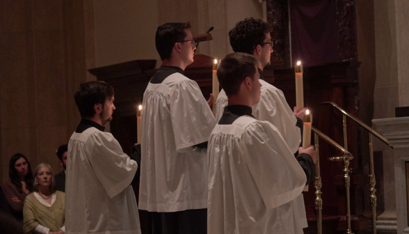 Four altar servers holding lit candles