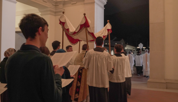 The priest holds the Eucharist under the canopy