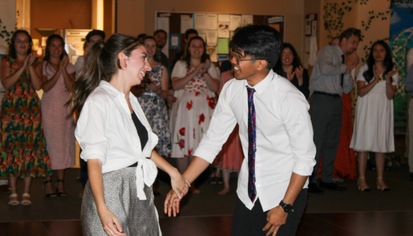 A couple dances as others applaud in the background