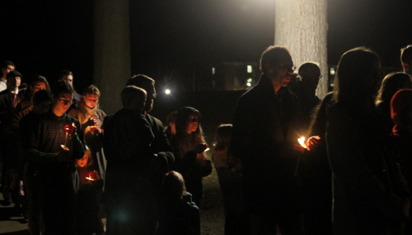 The congregation processes outdoors with candles in hands