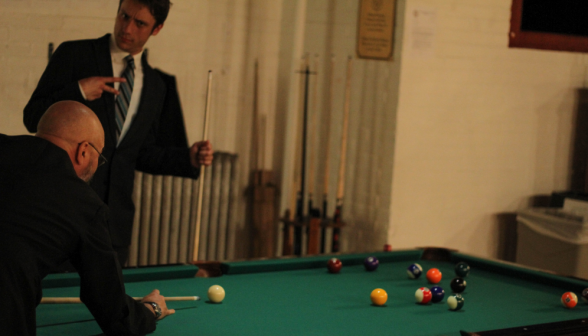 A student playing pool with Fr. Viego makes a face for the camera