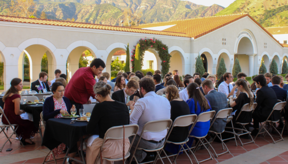 Students seated at long tables set up on the quad