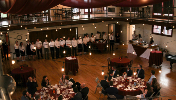 The table servers line up and are applauded by the guests