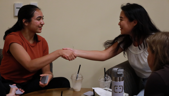 Two shake hands over a completed card game