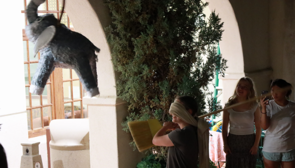 A student takes a swing at the pinata with a broom