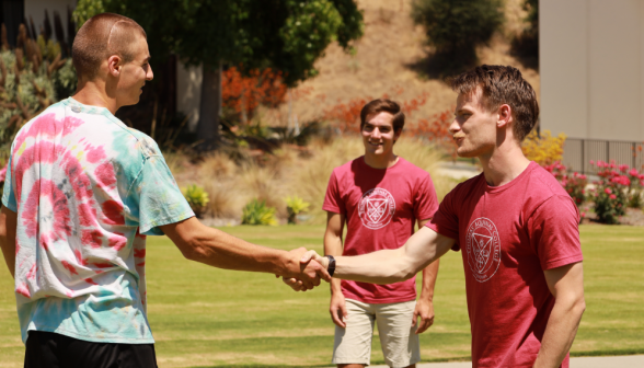 A prefect shakes hands with a student