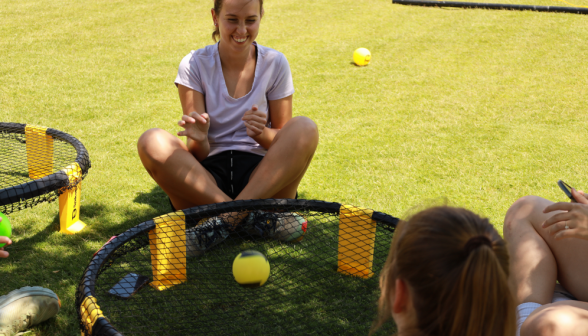 Several chat around a Spikeball net as if it's a campfire