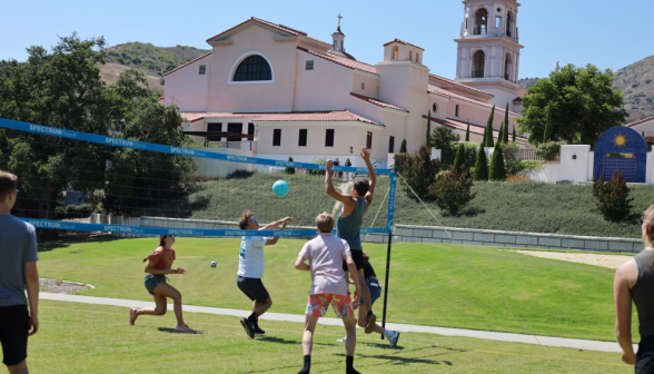 Students play volleyball on the sand court