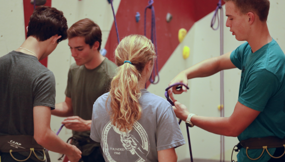 Students attach safety gear for rock climbing