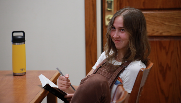 A student at a desk smiles for the camera