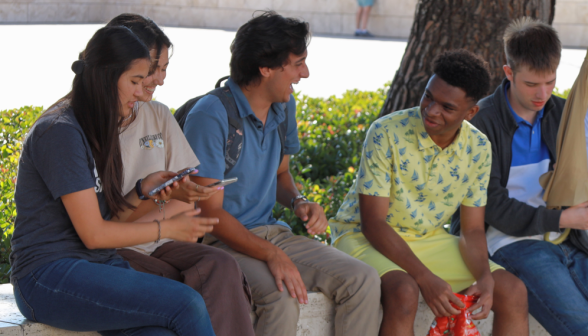 Five seated on an outdoor bench