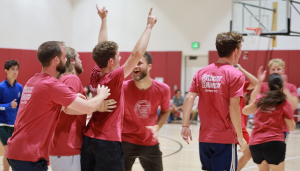 A student raises his hands in victory and is cheered by his teammates