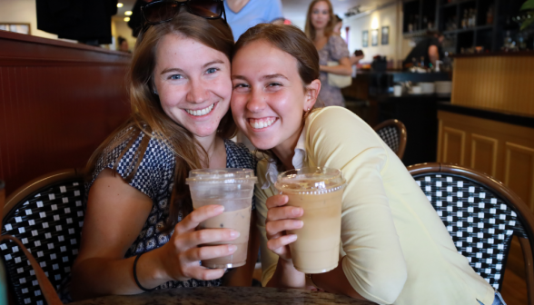 Two pose with coffees