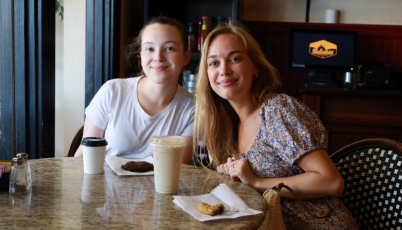 Two pose at their coffee-shop table