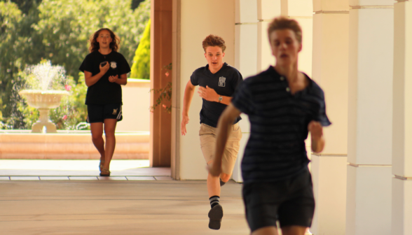 Two sprint while one in front of the fountain times them