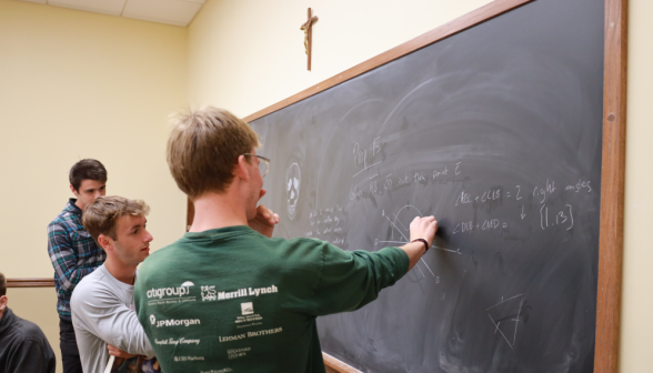 Two work on a prop together at the board