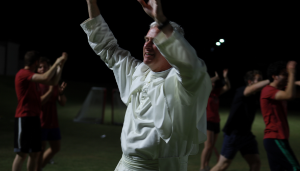 Fr. Walshe raises his hands in a cheer/blessing