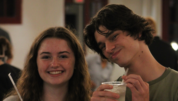 Two pose together in the coffee shop for a photo, drinks in hand