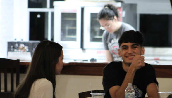 A student gives a thumbs-up at one of the tables