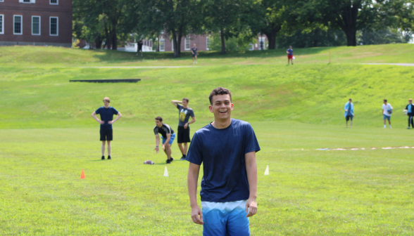 A student on the field smiles at the camera