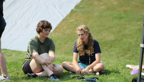 Two chat cross-legged in the grass