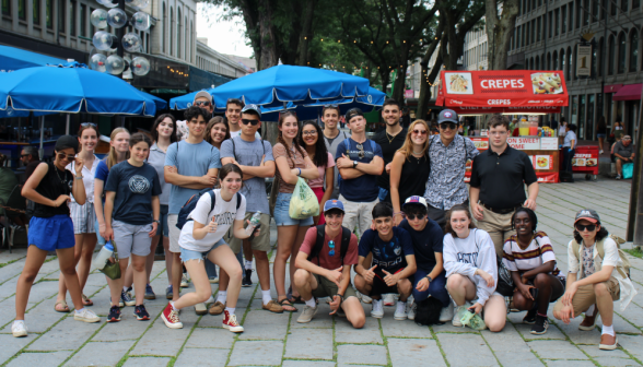 All the students pose together as a group afront picnic tables and a crepe stand