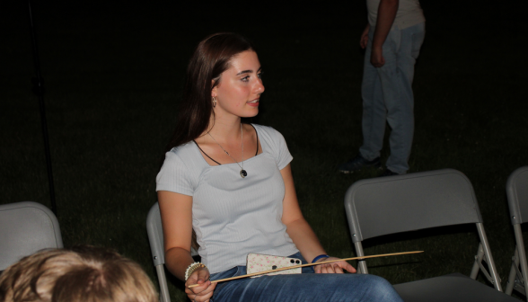 A student at the fire with a marshmallow stick