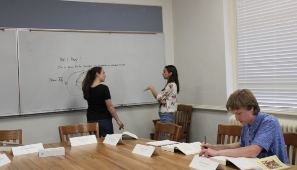 Two discuss a prop at the board