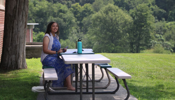 A student at one of the picnic tables outside the Commons