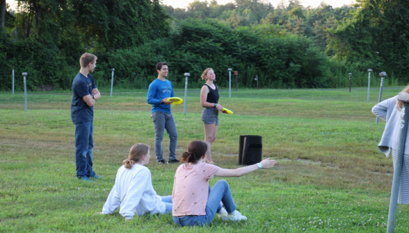 Two play Frisbee while three watch